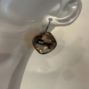 Peut inclure: Boucle d'oreille unique avec une pierre pr&eacute;cieuse en quartz fum&eacute;, carr&eacute;e et facett&eacute;e. La pierre est sertie dans un cadre en m&eacute;tal argent&eacute; et suspendue &agrave; un crochet simple. La boucle d'oreille est pr&eacute;sent&eacute;e sur fond blanc.