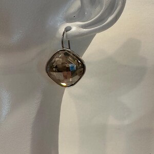 Peut inclure: Une boucle d'oreille unique avec une pierre pr&eacute;cieuse en quartz fum&eacute; taill&eacute;e en forme carr&eacute;e. La pierre est sertie dans un cadre en m&eacute;tal argent&eacute; et suspendue &agrave; un simple crochet. La boucle d'oreille est pr&eacute;sent&eacute;e sur fond blanc.
