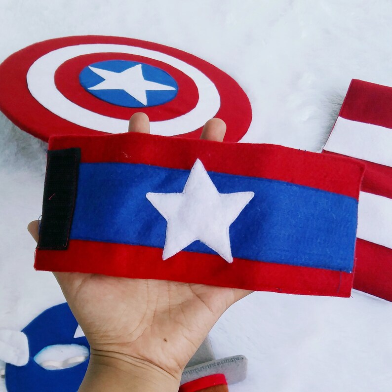 May include: Red, white, and blue felt armband with a white star in the center. The armband has a black velcro strap.