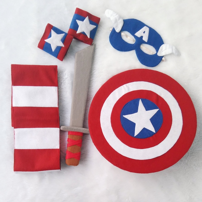 May include: A red, white, and blue Captain America costume set for kids. The set includes a shield, a sword, a mask, and arm bands.