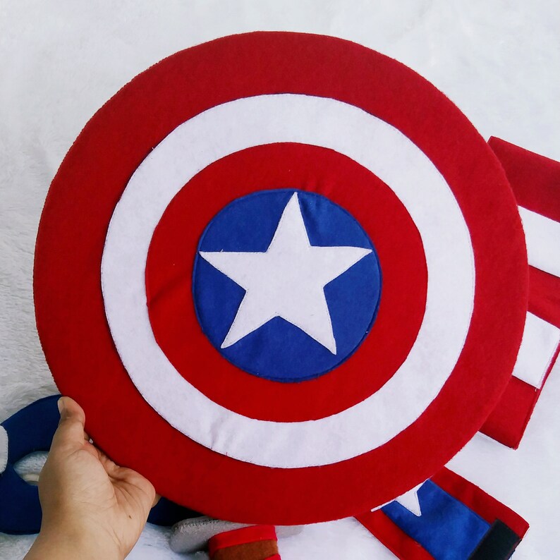 May include: A red, white, and blue felt Captain America shield with a white star on a blue circle in the center.