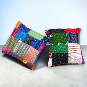 May include: Two square throw pillows featuring a patchwork design of quilted fabric squares. The pillows display a variety of colors including blue, green, red, yellow, and pink, with diverse patterns such as stripes, dots, and floral motifs.