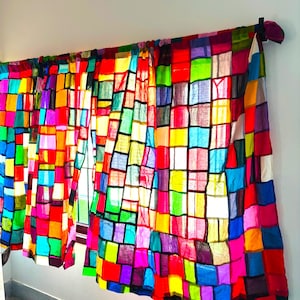 May include: Colorful patchwork curtains with a vibrant array of squares in red, yellow, blue, green, and purple. The curtains are hanging on a rod, adding a pop of color to the room. The design is a mix of bright and bold hues.