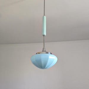 May include: A vintage-style pendant light fixture. It features a light blue, ribbed glass shade and a chrome-colored metal stem. The fixture has a cylindrical light blue accent and a chrome-colored ceiling mount.