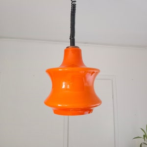 May include: Orange glass pendant light with a black cord and ceiling mount.