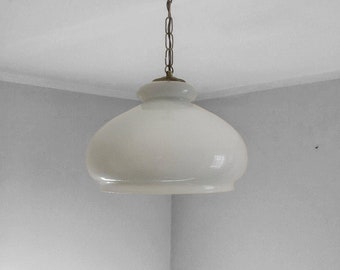 May include: A vintage-style pendant light fixture with a white, rounded glass shade. The fixture has a copper-colored canopy and a chain with brass-colored links. The light hangs from the ceiling, showcasing a classic design.