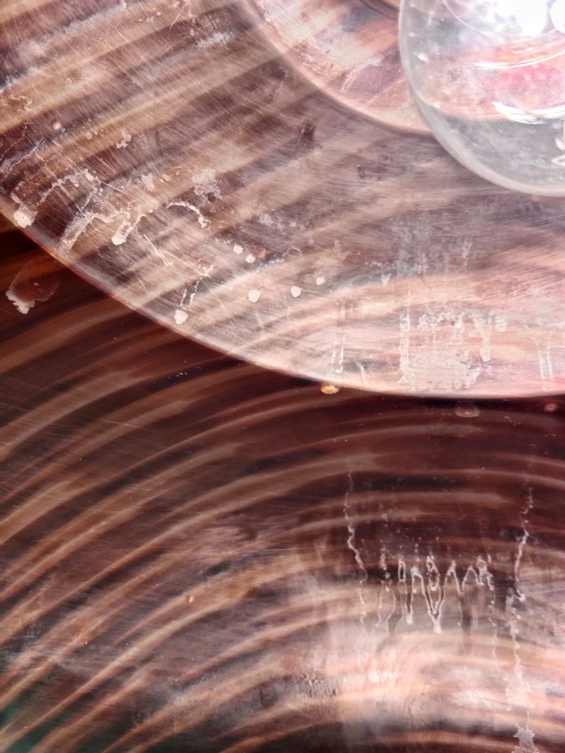 May include: Close-up of a brown and black wooden bowl with a swirling pattern. The bowl has a smooth, polished surface and is slightly weathered.