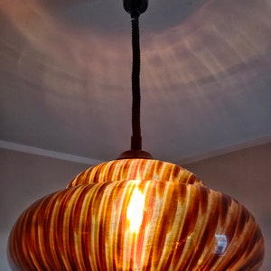 May include: A brown and gold striped glass pendant light fixture with a black cord.