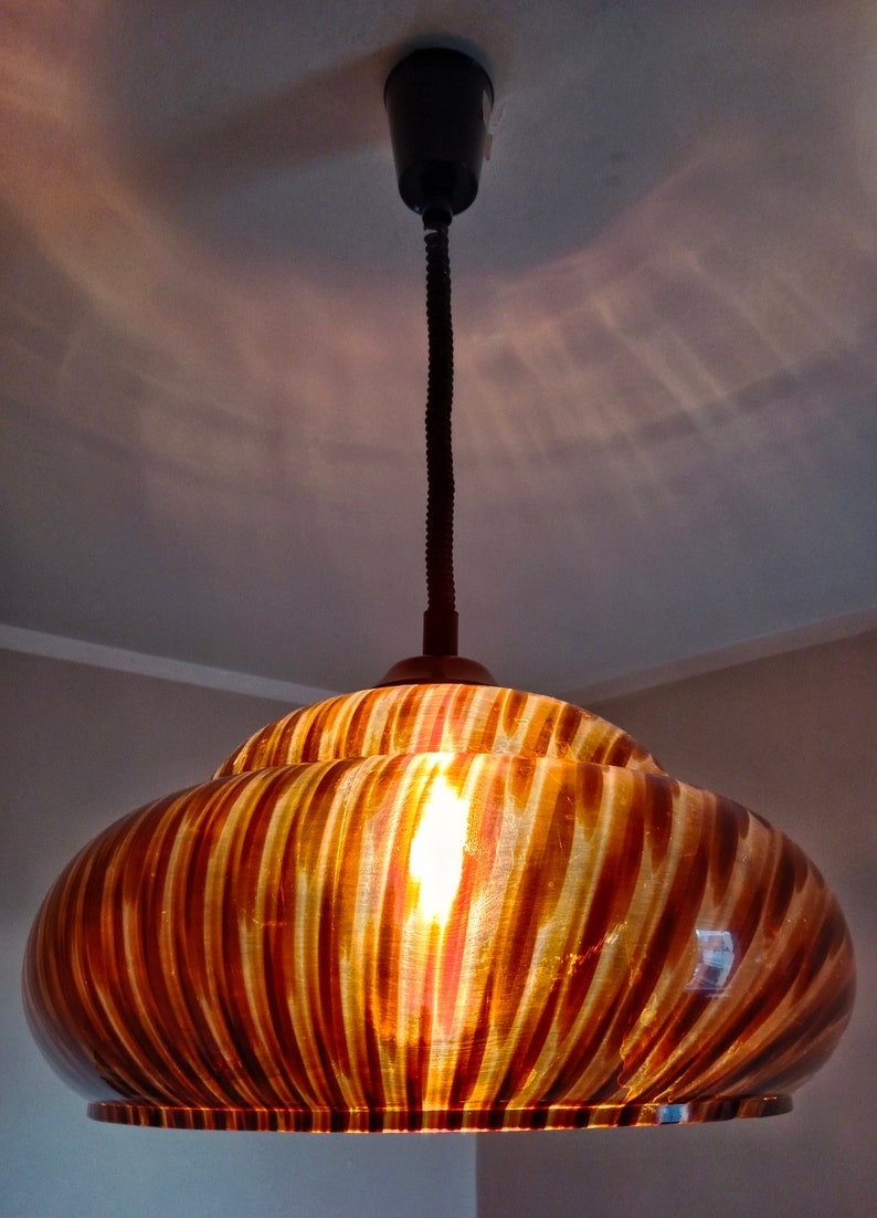 May include: A brown and gold striped glass pendant light fixture with a black cord.