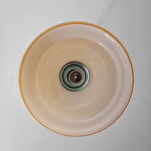 May include: A white ceiling light fixture with a gold rim and a silver center. The light is turned off.