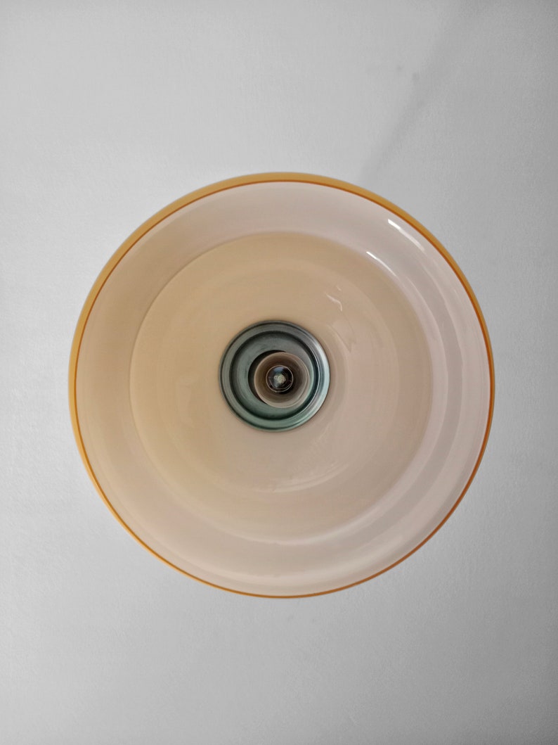 May include: A white ceiling light fixture with a gold rim and a silver center. The light is turned off.