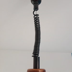 May include: A black ceiling fixture with a coiled cord and an orange glass shade.