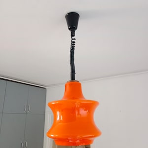 May include: Orange glass pendant light with a black cord and a black ceiling mount.