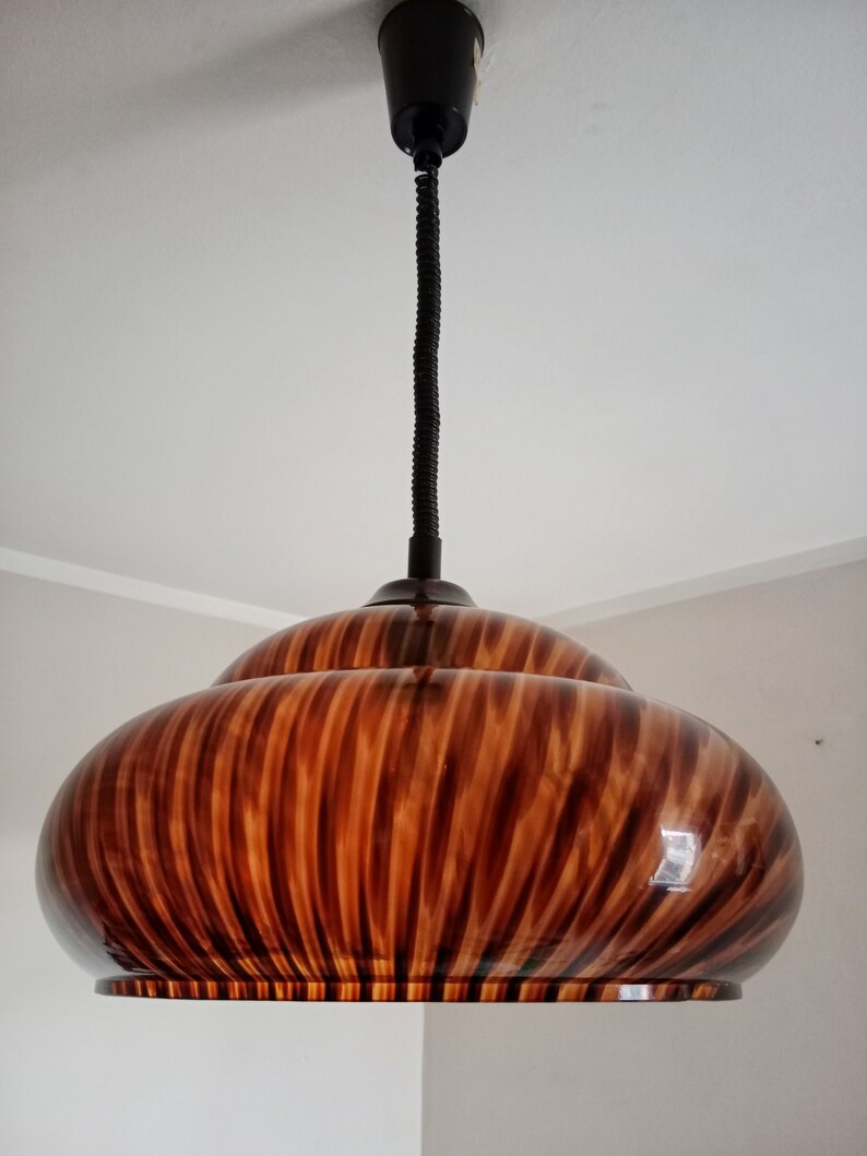 May include: A brown and black striped pendant light fixture with a black cord.