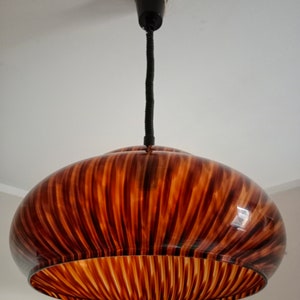 May include: A brown and black striped glass pendant light fixture with a black cord.