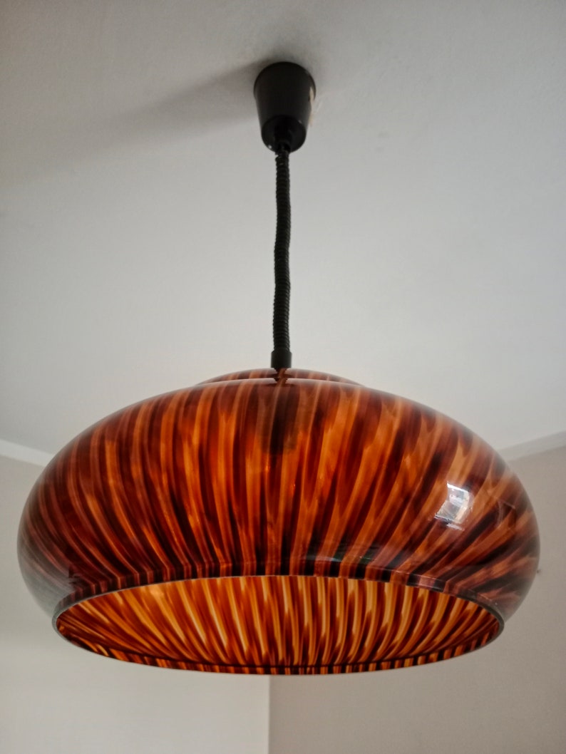 May include: A brown and black striped glass pendant light fixture with a black cord.
