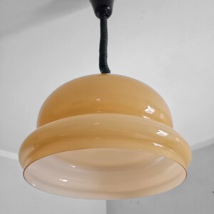May include: A beige glass pendant light fixture with a black cord hanging from the ceiling.