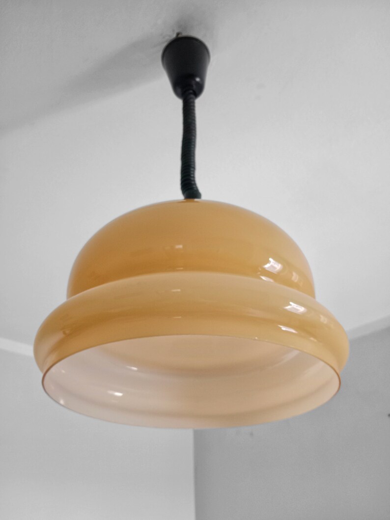 May include: A beige glass pendant light fixture with a black cord hanging from the ceiling.