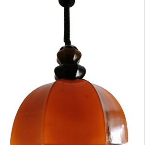 May include: A brown and black pendant light with a dome-shaped shade. The shade is made of glass and has a textured surface. The light is suspended from a black metal cord.
