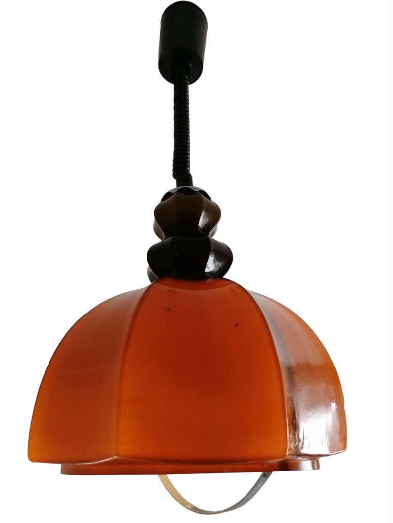 May include: A brown and black pendant light with a dome-shaped shade. The shade is made of glass and has a textured surface. The light is suspended from a black metal cord.