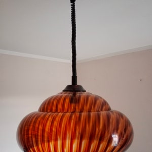 May include: A brown and white striped pendant light with a black cord.