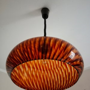 May include: A brown and white striped pendant light fixture with a round, bowl-shaped shade.