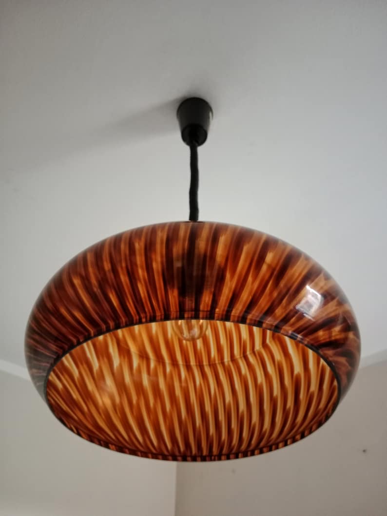 May include: A brown and white striped pendant light fixture with a round, bowl-shaped shade.