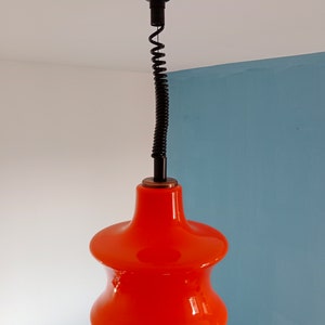 May include: A bright orange glass pendant light with a black cord and a black ceiling mount.