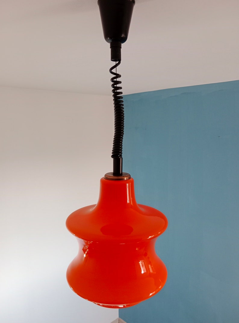 May include: A bright orange glass pendant light with a black cord and a black ceiling mount.