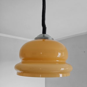 May include: A yellow glass pendant light with a black flexible cord.