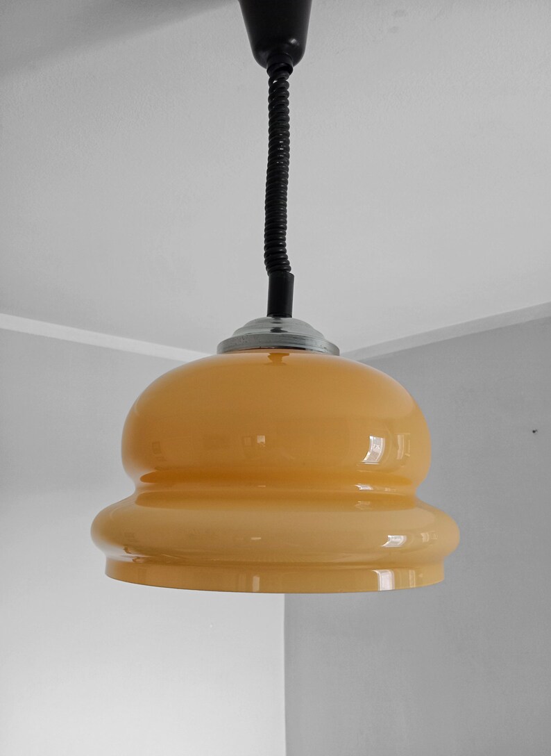 May include: A yellow glass pendant light with a black flexible cord.