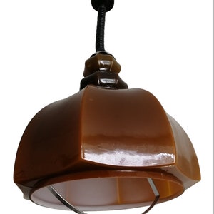 May include: A brown glass pendant light with a metal ring around the bottom. The light has a black cord and a black ceiling mount.