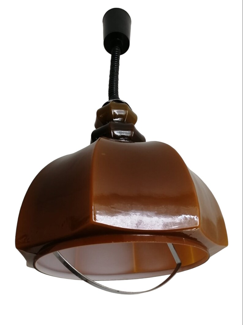 May include: A brown glass pendant light with a metal ring around the bottom. The light has a black cord and a black ceiling mount.