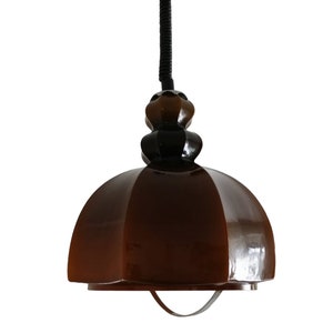 May include: A brown glass pendant light with a black cord and a black metal base. The light has a dome shape and a textured surface.