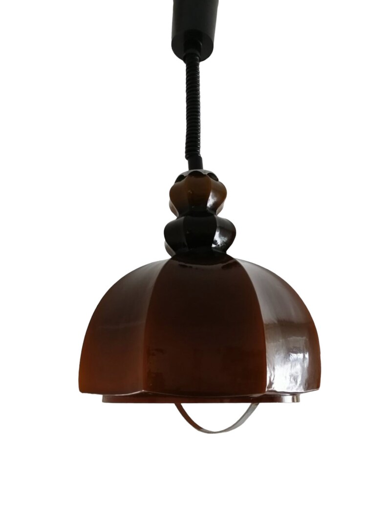 May include: A brown glass pendant light with a black cord and a black metal base. The light has a dome shape and a textured surface.