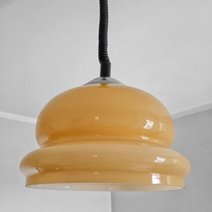 May include: A yellow glass pendant light with a black cord hanging from the ceiling.