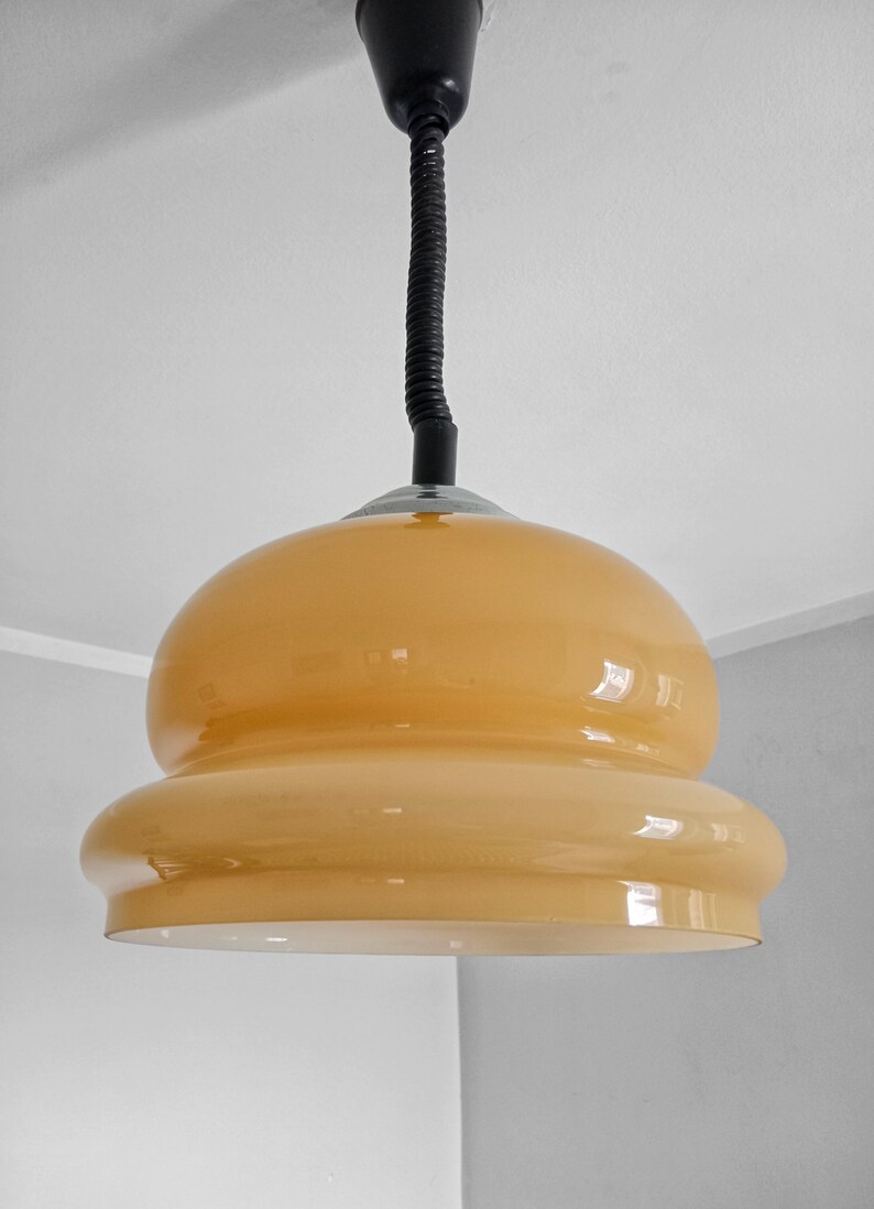 May include: A yellow glass pendant light with a black cord hanging from the ceiling.