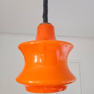 May include: A bright orange glass pendant light with a black cord.