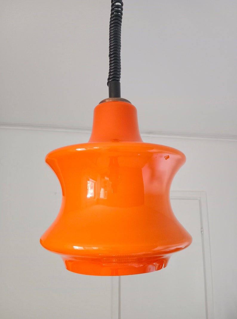 May include: A bright orange glass pendant light with a black cord.