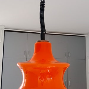 May include: Orange glass pendant light with a black cord and a black ceiling mount.