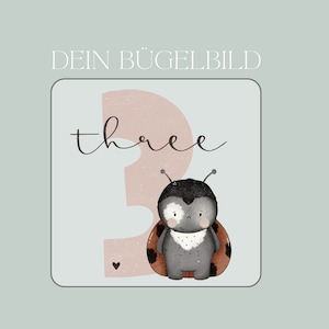 Könnte beinhalten: Ein rosa-weißes Bügelbild mit dem Wort "three" und einem Cartoon-Marienkäfer. Der Marienkäfer ist schwarz mit roten Punkten und hat einen weißen Kragen.