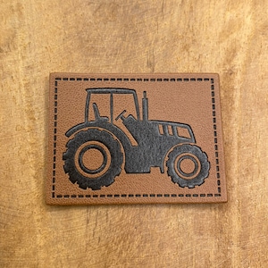 Peut inclure: Un patch en cuir marron avec une silhouette noire de tracteur. Le patch a une bordure cousue.