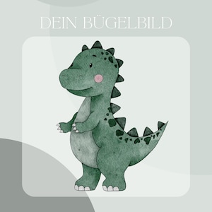 May include: A green dinosaur with a pink blush on its cheek, standing on a white background. The text "DEIN BÜGELBILD" is above the dinosaur and the text "Inklusive Anleitung und Test-Bügelbild" is below the dinosaur.