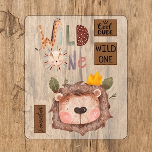 Op de afbeelding: Een bruin houten bord met een illustratie van een leeuw en een giraffe. Het bord zegt "Wild One" met een kroon boven het woord "Cool Dude".