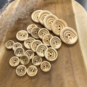 May include: A collection of wooden buttons featuring a rainbow and heart design. The buttons are light brown and have a natural wood finish.