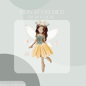 May include: A watercolour illustration of a fairy with brown hair, a yellow skirt, and white wings. The fairy is wearing a floral crown and surrounded by butterflies. Text at the top reads "DEIN BÜGELBILD" and "19cm x 12cm".
