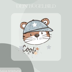 Könnte beinhalten: Ein Bügelbild mit einem gezeichneten Tigerkopf, der eine gesprenkelte blaue Baseballkappe mit einem weißen Stern trägt. Unter dem Tiger steht das Wort Cool in einer dunkelbraunen Schreibschrift, umgeben von kleinen grauen und orangefarbenen Sternen.