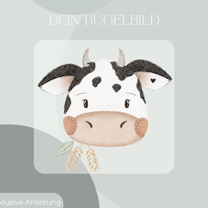 Può includere: Illustrazione ad acquerello di una faccia di mucca con segni bianchi e neri, piccole corna e un rametto di grano. Il testo "DEIN BÜGELBILD" è in alto e "Inklusive Anleitung und Test-Bügelbild" in basso.
