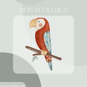 Peut inclure: Un perroquet rouge et bleu avec un long bec perché sur une branche avec des feuilles vertes. Le texte "DEIN BÜGELBILD" est au-dessus du perroquet. Le texte "Inklusive Anleitung und Test-Bügelbild" est en dessous du perroquet.