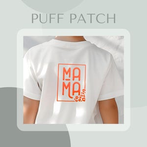 May include: White t-shirt with a red "MAMA" graphic in a square frame. The graphic is surrounded by small orange leopard print spots.